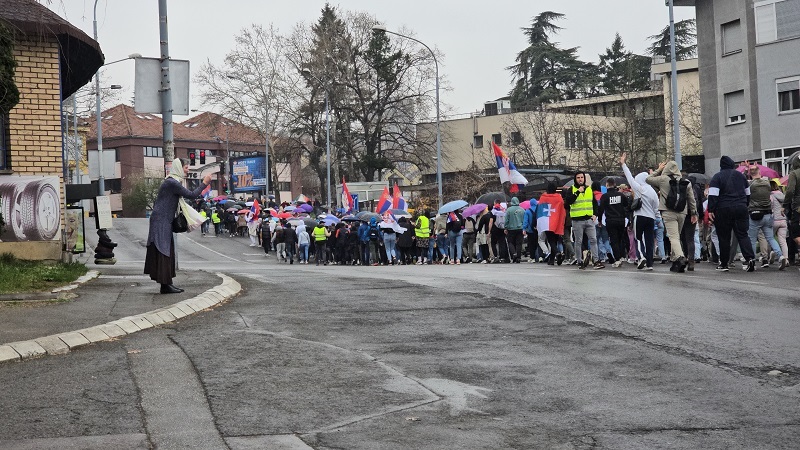 Ženska se križa in priklanja demonstrantom na Voždovcu