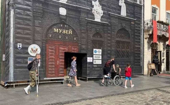 Lvov, slika, ki kaže vso tragedijo Ukrajine v enem prizoru: invalidi pred ameriškim grbom.