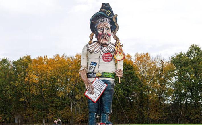 Lutka s podobo britanskega premierja je visoka 11 metrov, nosi klobuk, japonke in gorečo baklo z napisom »Prilizujem se Trumpu«. Vir: Posnetek zaslona, X