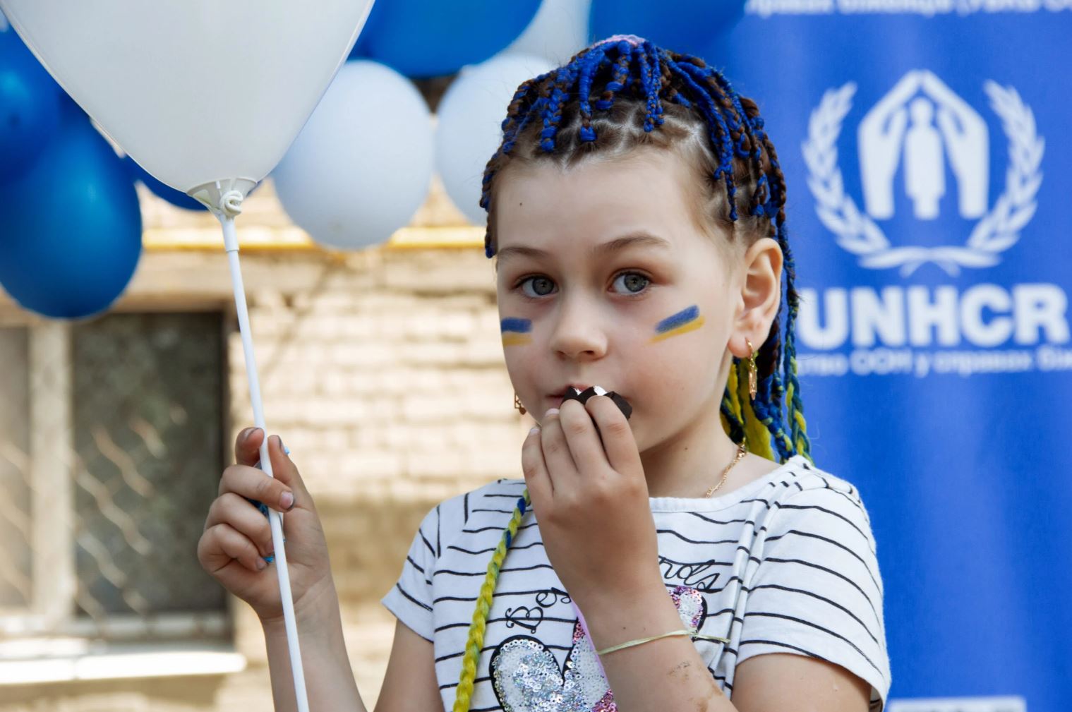 Ukrajinski otrok pred panojem UNHCR Vir: UNHCR